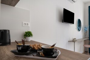 Eine moderne Küche mit Kaffeemaschine, einer Pflanze und einem Tablett mit zwei Tassen und Gebäck.