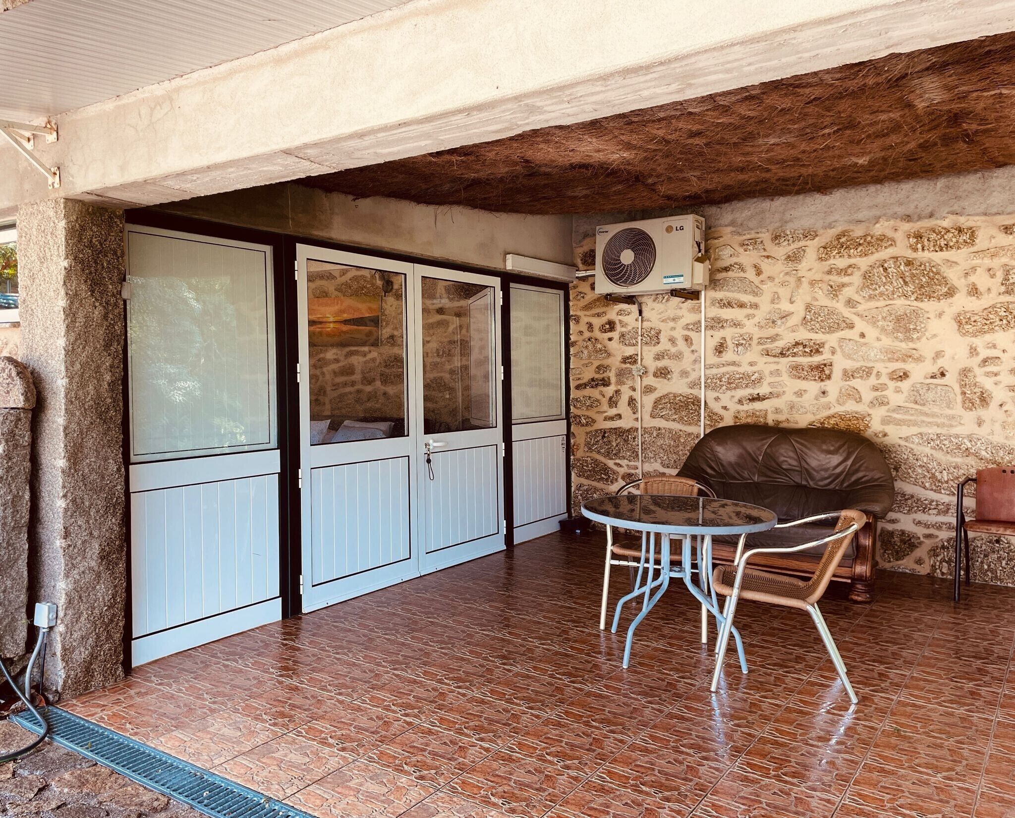 Une pièce avec un mur en pierre, un ventilateur de plafond, une table avec des chaises et une porte coulissante.
