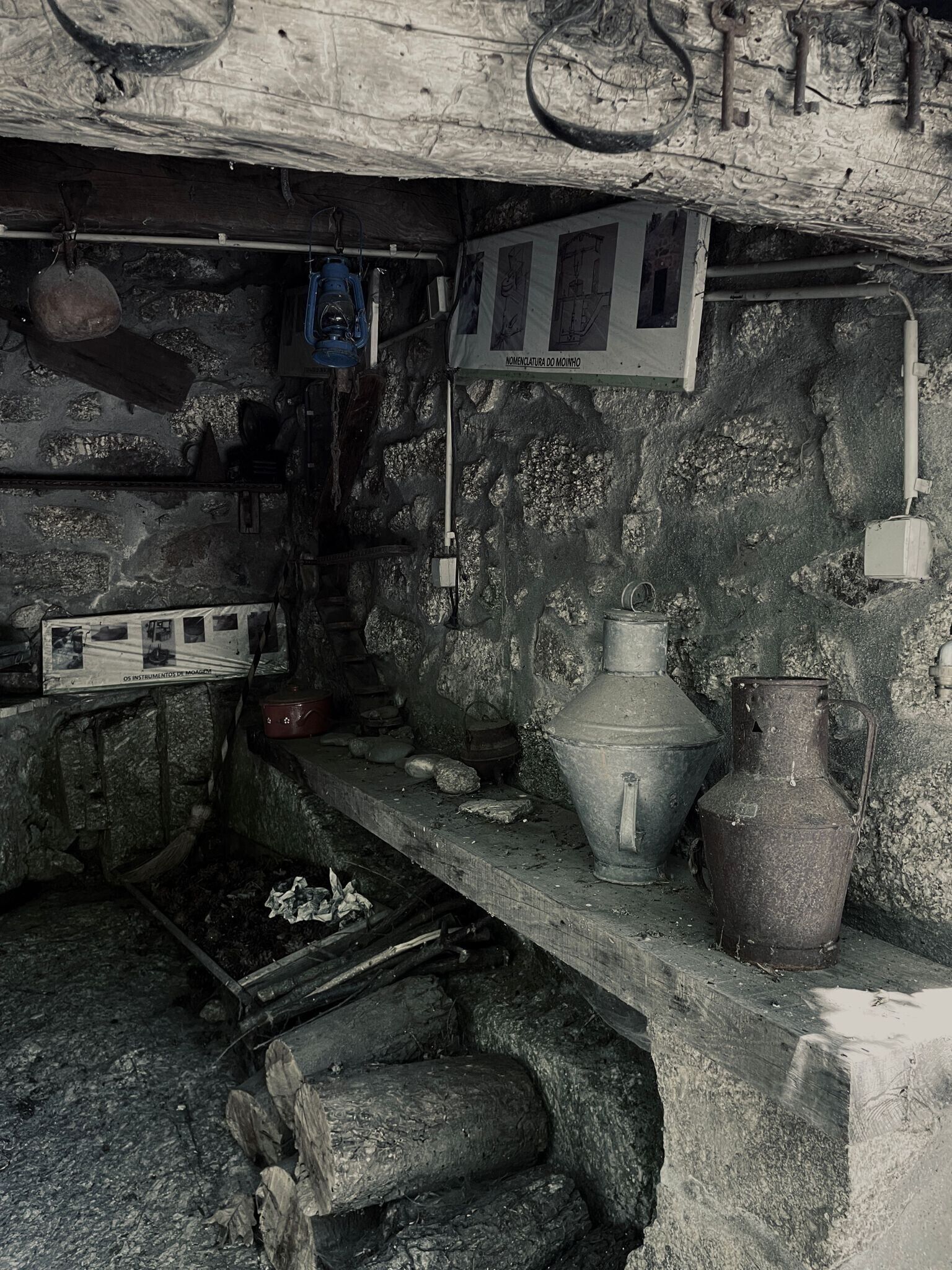 Une cuisine rustique avec un mur en pierre, une étagère en bois et une marmite en métal.
