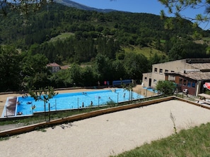 A swimming pool surrounded by a sandy area with a building in the background.
