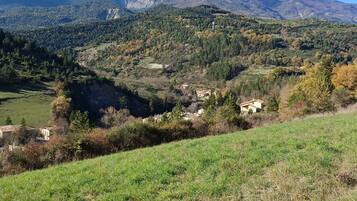 Un paisaje montañoso con un valle, casas dispersas y un cielo despejado.