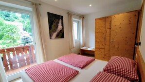 Camera da letto con due letti, un armadio in legno, una finestra con vista sul verde e un quadro appeso al muro.