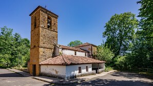 Un edificio histórico con una torre de campanas, un patio interior y un camino adoquinado.