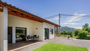 Un edificio con un patio, mobiliario exterior y vistas a las montañas.