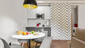 Una cocina moderna con armarios blancos, microondas y un comedor con mesa redonda y sillas.