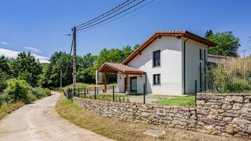 A two-story house with a stone wall and a paved driveway.