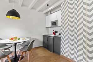 Cozinha compacta com micro-ondas, geladeira e área de jantar com mesa e cadeiras.