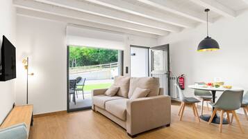 Een moderne woonkamer met een bank, eettafel, stoelen en een televisie.
