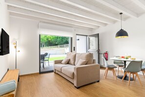 Uma sala de estar moderna com sofá, mesa de jantar, cadeiras e televisão.