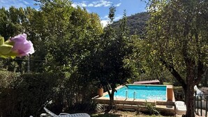 A backyard with a swimming pool, a tree, and a white lounge chair. - Casa Rural Orilla del Hueznar – Relax en la Sierra Norte de Sevilla (Cazalla de la Sierra)