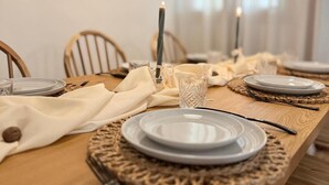 A dining table set with plates, cutlery, and candles, with chairs around it. - Casa Rural Orilla del Hueznar – Relax en la Sierra Norte de Sevilla (Cazalla de la Sierra)