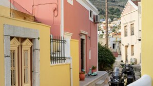Una calle estrecha con edificios, una moto y una ciclomotor estacionadas al costado.