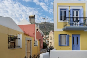 Eine enge Straße mit bunten Häusern, ein Berg im Hintergrund und ein klarer Himmel.