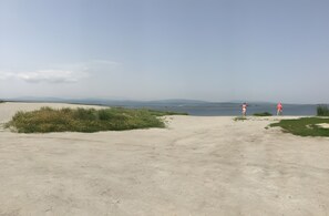 A sandy beach with two people in the distance, a clear sky, and distant mountains. - Holiday Home 'Mas Iles Des Pecheurs' with Sea View, Shared Pool and Wi-Fi (Le Barcarès)