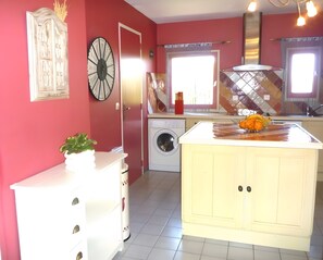 A kitchen with a washing machine, a clock, and a sink. - Holiday Home 'Mas Iles Des Pecheurs' with Sea View, Shared Pool and Wi-Fi (Le Barcarès)