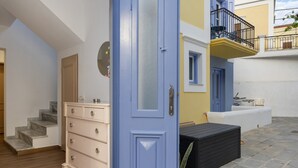 A room with a blue door, a white dresser, a staircase, and a balcony with a railing. - Room 'Double  3' with Private Terrace, Wi-Fi and Air Conditioning (Ano Symi)