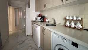 A kitchen with a washing machine, a sink, cabinets, and a microwave. - Bright 2BR in Taksim Near Acıbadem Hospital (Istanbul)