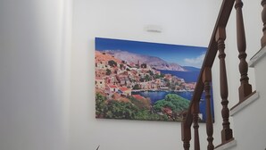 A staircase with marble steps, a potted plant, and a painting of a coastal town. - Studio '11' with Private Balcony, Kitchenette, Wi-Fi and Air Conditioning (Ano Symi)