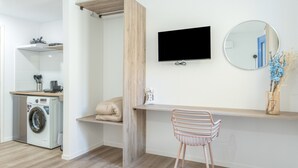 Een moderne badkamer met een wasmachine, een houten wastafelmeubel, een spiegel en een stoel.