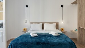 Ein Hotelzimmer mit einem Bett, zwei Nachttischen, einem Schrank und Blick ins Freie.