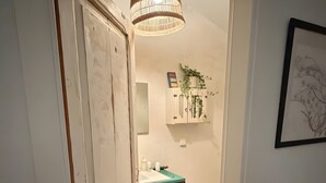A hallway leading to a bathroom with a sink, a hanging light fixture, and a framed picture on the wall. - Sítio do Valverde Coruche (Coruche)