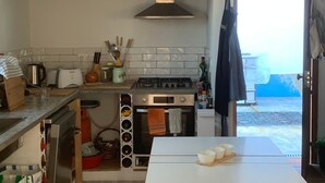 A kitchen with a white table, a stove, and a hanging apron. - Sítio do Valverde Coruche (Coruche)