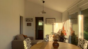 A dining area with a wooden table, chairs with floral upholstery, a vase, and a ceiling fan. - Sítio do Valverde Coruche (Coruche)