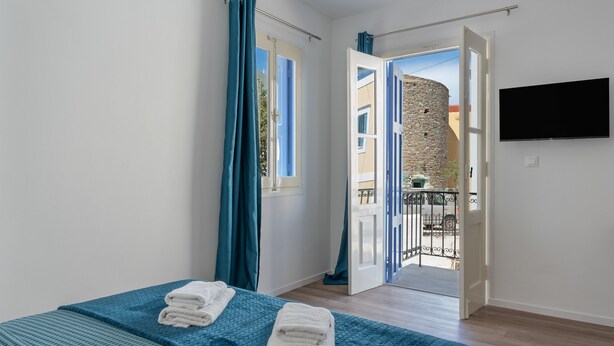Una camera da letto con un letto, una televisione e un balcone con parete in pietra e ringhiera.