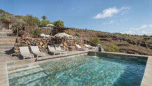 A clear pool with stone steps leading up to lounge chairs and a stone wall. - Vacation Home 'Karla' with Sea View, Shared Pool and Wi-Fi (Cruz de Tea)