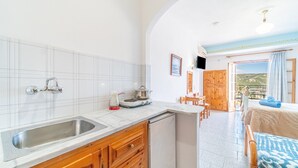 Una cocina con pileta, estufa y armarios de madera, que da a un comedor con mesa y sillas.
