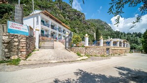 Hotel con entrada de pared de piedra, un letrero y montañas al fondo.