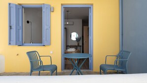 Een kamer met een gele wand, een blauwe deur en een blauwe tafel met twee stoelen.