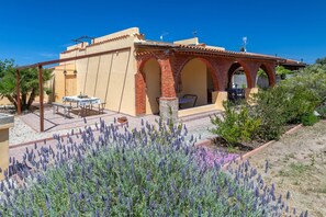 Un edificio con un patio, mobiliario exterior y un jardín de lavanda.