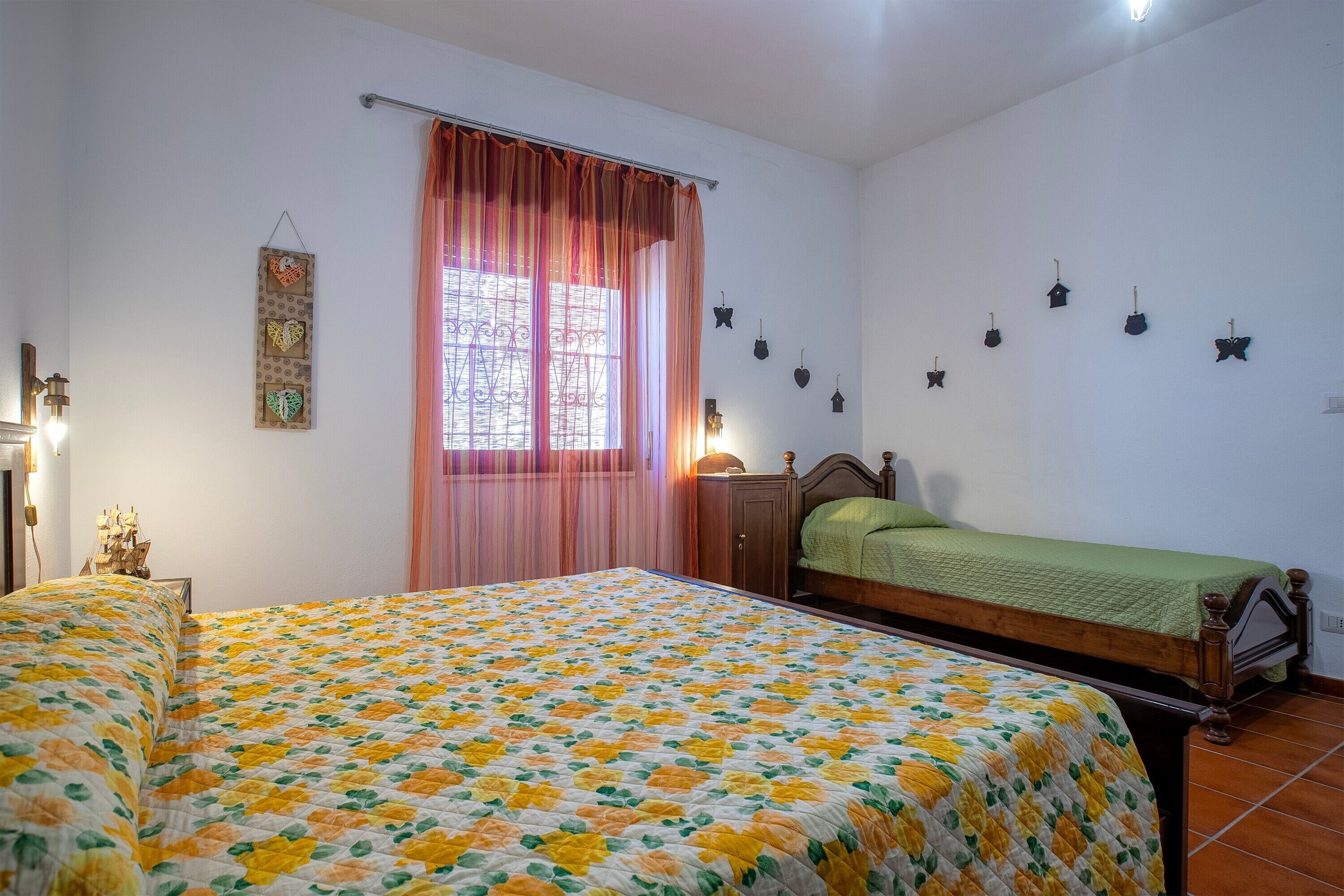 Une chambre avec deux lits, une fenêtre avec des rideaux, des décorations murales et une table de chevet avec une lampe.