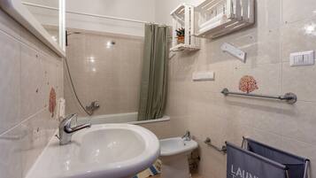 A bathroom with a sink, bidet, and shower.