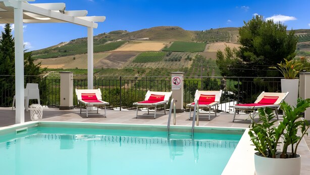 A pool area with lounge chairs and a view of the hills.