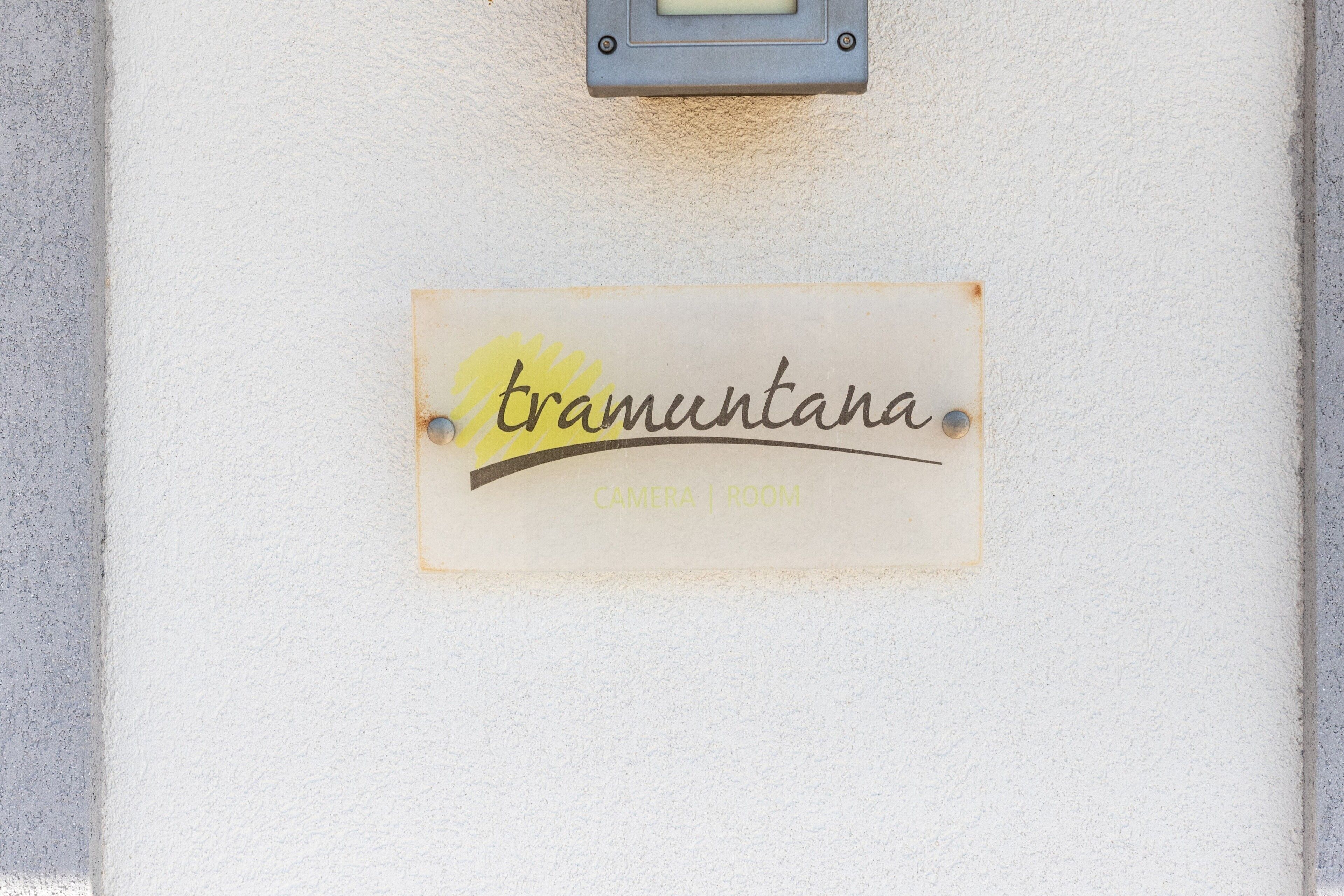 A wall-mounted sign with the text 'tramutana' and 'CAMERA | ROOM' indicating a room number or designation.