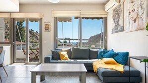 A modern living room with a sofa, a coffee table, and a view of the sea. - Elva Creta Beach Apartment with Sea View, Wi-Fi, and Air Conditioning (Palaiokastro)