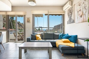 A modern living room with a sofa, a coffee table, and a view of the sea. - Elva Creta Beach Apartment with Sea View, Wi-Fi, and Air Conditioning (Palaiokastro)