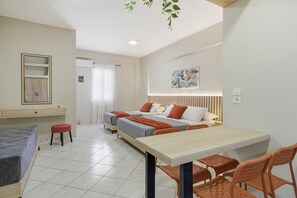 Ein Hotelzimmer mit einem Bett, einem Schreibtisch, einem Sessel, einem kleinen Hocker und einem Wandregal.