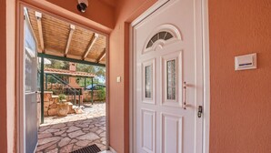 A doorway leading to an outdoor patio with stone flooring and a covered seating area. - Studio Apartment '6' with Shared Garden, Wi-Fi and Air Conditioning (Syvota)