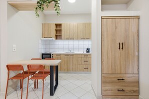 Eine Küche mit Holzausstattung, einer weißen Fliesenwand, einem Esstisch mit Stühlen und einem Holzschrank.