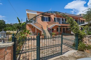 Ein zweigeschossiges Haus mit einer Steintreppe, einem Metallgitter und einem Garten.