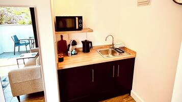 A compact kitchen with a microwave, sink, and coffee maker.