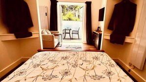 Un dormitorio con una cama grande, un sofá, una mesa y vistas al exterior.