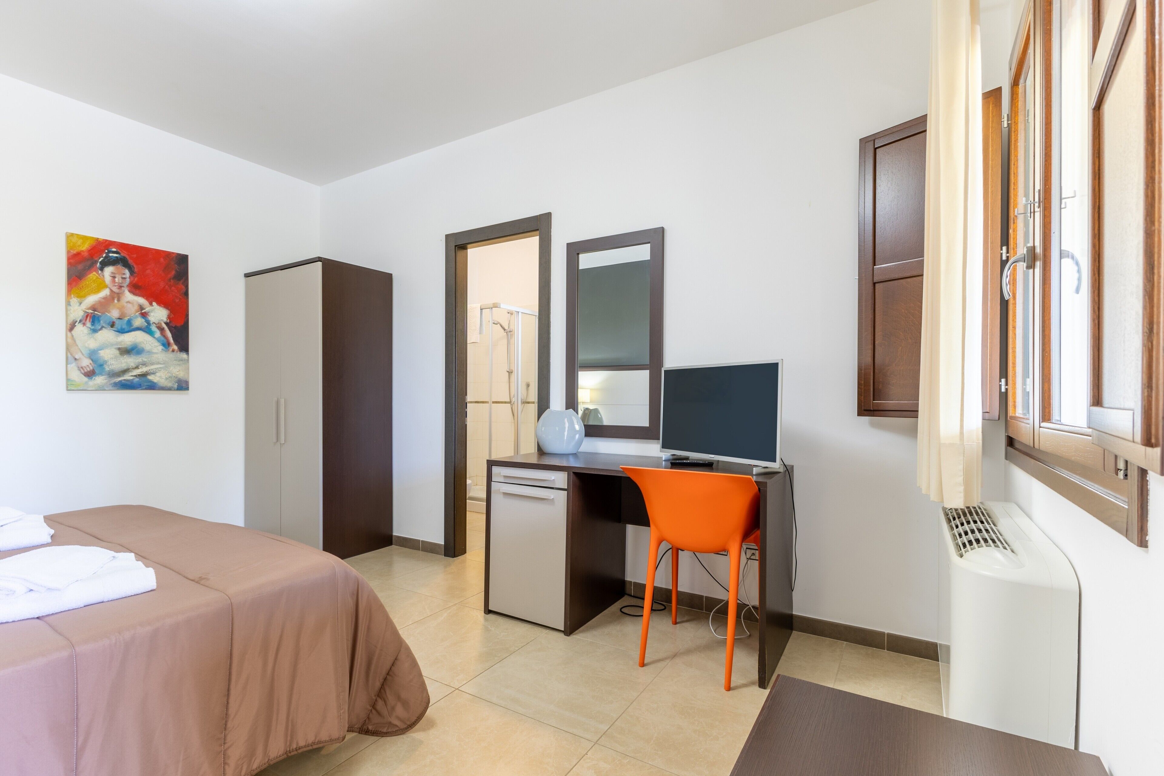 Una habitación de hotel con cama, escritorio, silla y televisor.