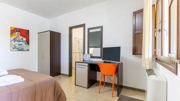 Una habitación de hotel con cama, escritorio, silla y televisor.
