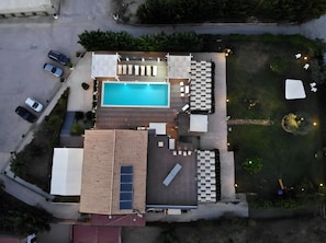 Vista aérea de una propiedad con piscina, mobiliario de exterior y un patio cubierto.