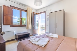 A bedroom with a bed, a desk, a wardrobe, and a sliding glass door leading to a balcony. - 'Sciauru' Room with Shared Outdoor Pool, Wi-Fi and Air Conditioning (Mazzarino)