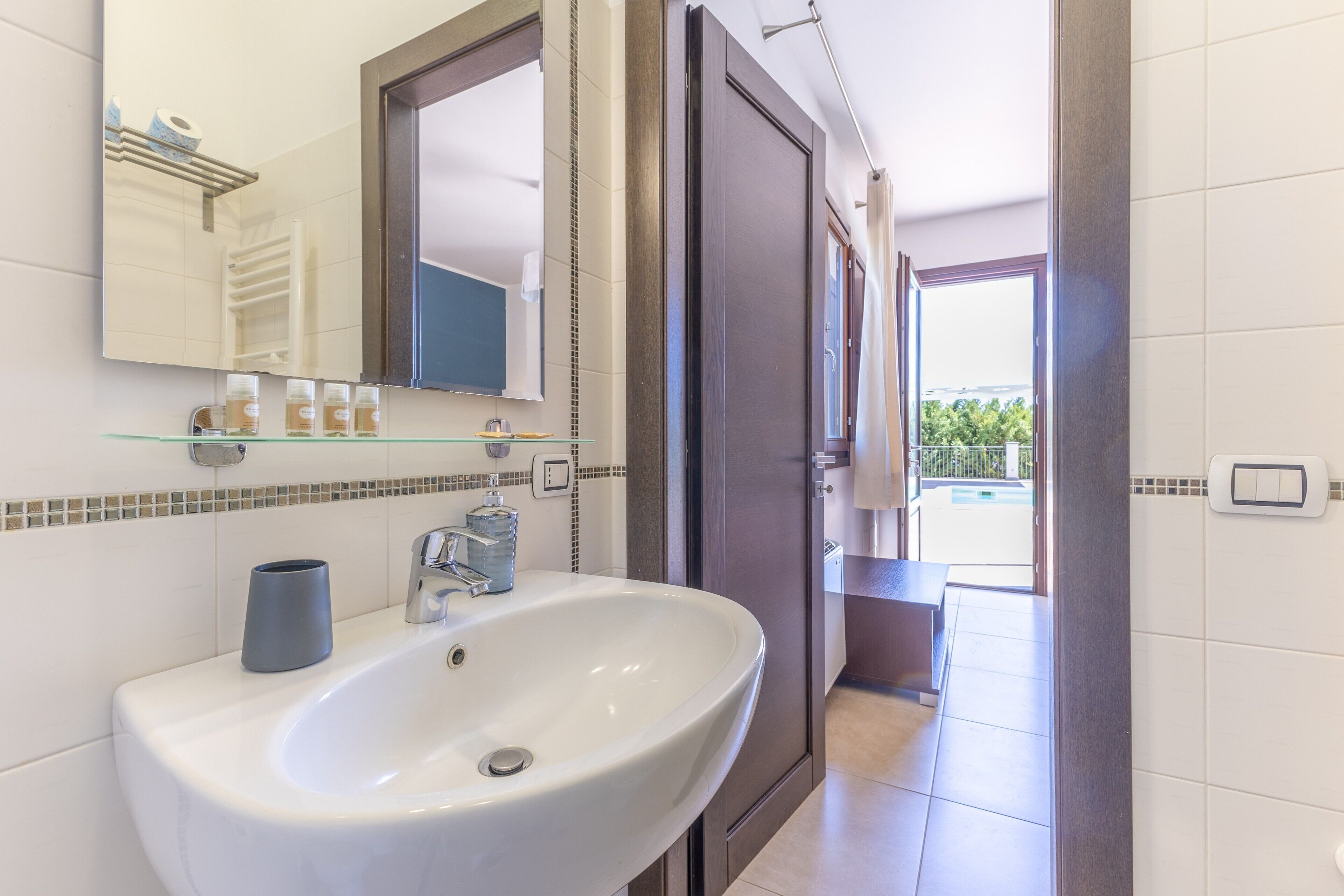 A bathroom with a white sink, a mirror, and a shower area.